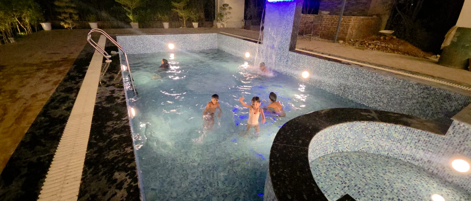 Swimming pool at night with waterfall and mood lighting